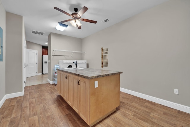 kitchen with washer and clothes dryer, a kitchen island, light wood-type flooring, and white fridge with ice dispenser