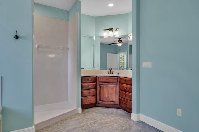 bathroom featuring walk in shower, vanity, and ceiling fan