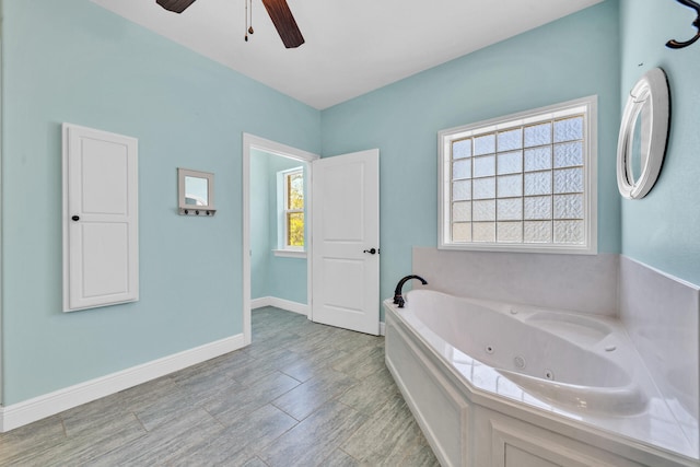 bathroom with a washtub, a healthy amount of sunlight, wood-type flooring, and ceiling fan