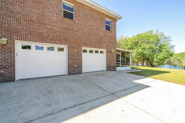 view of home's exterior featuring a sunroom, a yard, and a garage