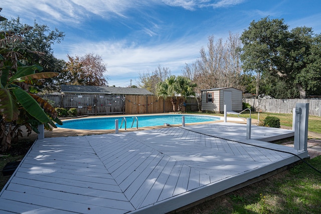 view of pool with a wooden deck and a storage shed