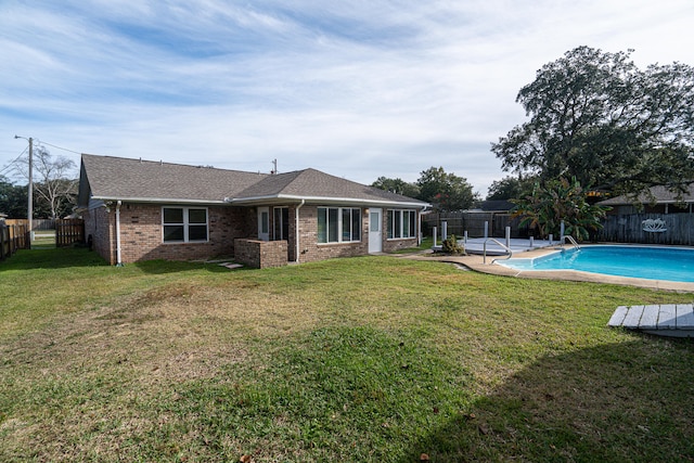 back of property with a yard and a fenced in pool