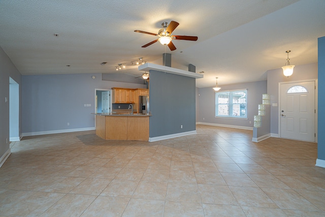 unfurnished living room featuring ceiling fan, sink, light tile flooring, vaulted ceiling, and track lighting