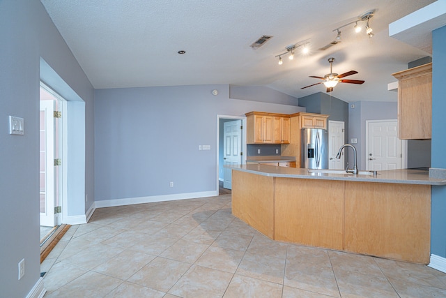 kitchen with ceiling fan, stainless steel fridge, vaulted ceiling, kitchen peninsula, and track lighting