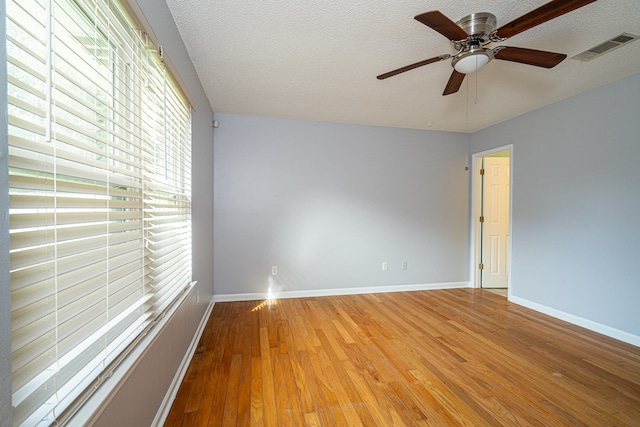 empty room featuring light hardwood / wood-style flooring, ceiling fan, and a textured ceiling