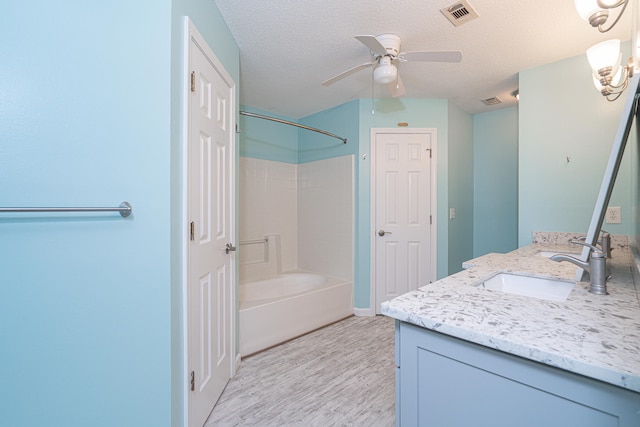 bathroom featuring a textured ceiling, ceiling fan, vanity, and bathing tub / shower combination