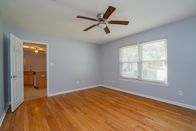 unfurnished room with light hardwood / wood-style flooring, ceiling fan, and a textured ceiling