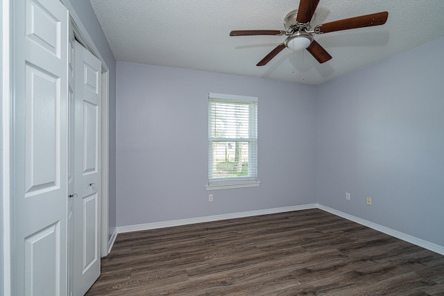 empty room featuring a textured ceiling, ceiling fan, and dark wood-type flooring