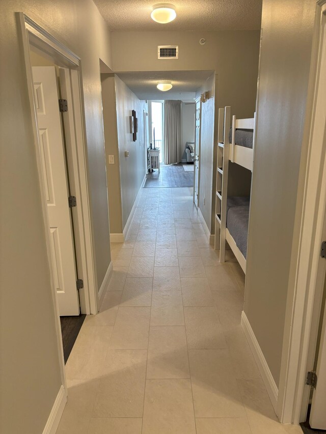 corridor with light tile patterned floors and a textured ceiling