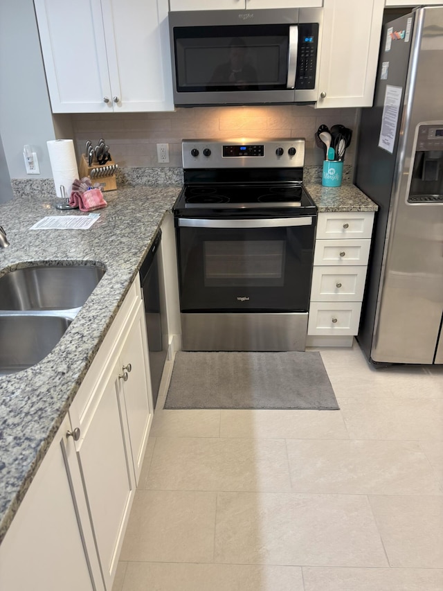 kitchen with sink, light tile patterned floors, light stone counters, white cabinets, and appliances with stainless steel finishes