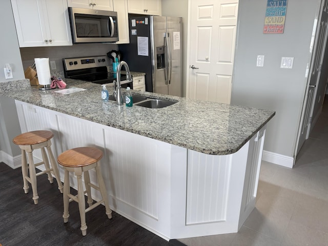 kitchen featuring kitchen peninsula, stainless steel appliances, and white cabinetry