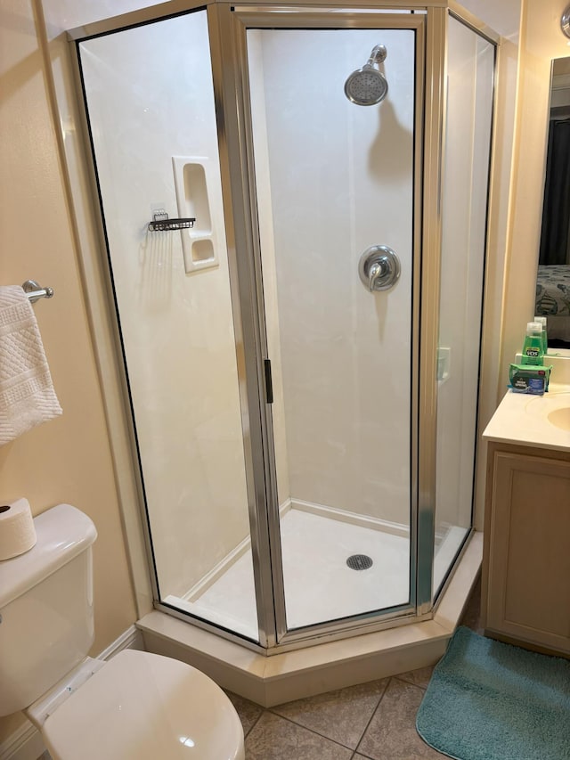 bathroom featuring tile patterned flooring, vanity, toilet, and walk in shower