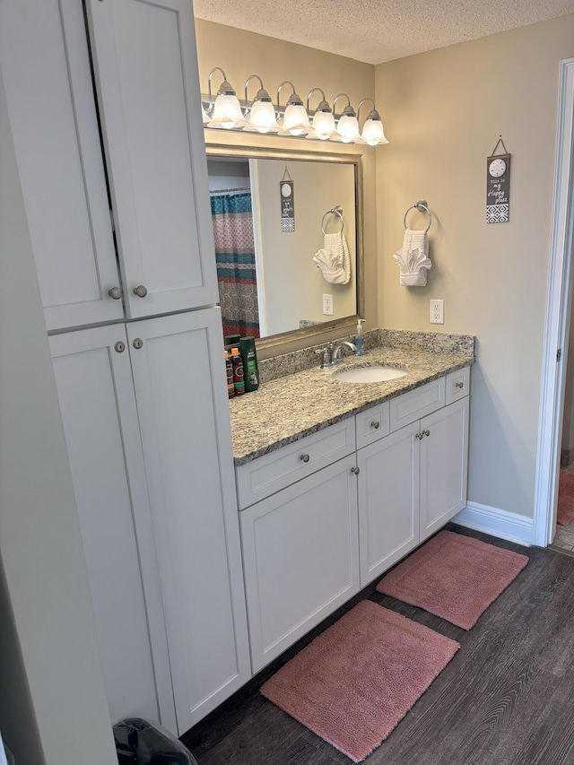 bathroom with hardwood / wood-style floors, vanity, and a textured ceiling