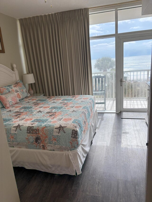 bedroom featuring hardwood / wood-style flooring, a water view, and access to outside