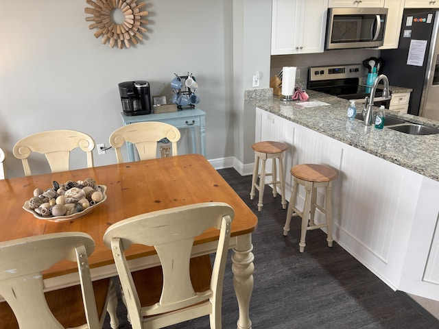 kitchen featuring sink, stainless steel appliances, light stone counters, dark hardwood / wood-style flooring, and white cabinets