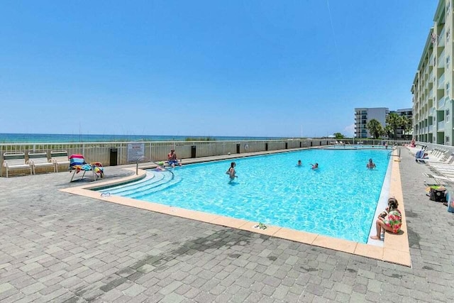 view of swimming pool featuring a water view and a patio