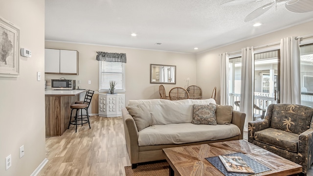 living room featuring light hardwood / wood-style flooring, ceiling fan, and ornamental molding