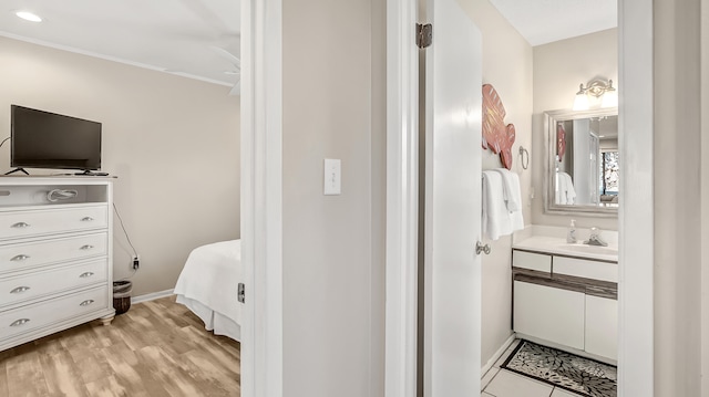 bedroom with ornamental molding, sink, and light wood-type flooring