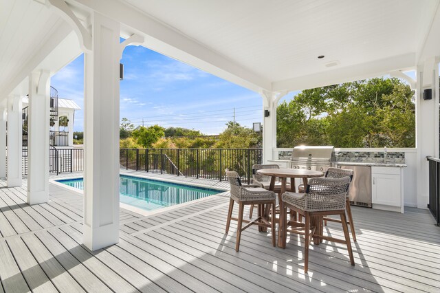 wooden terrace featuring a fenced in pool, an outdoor kitchen, and area for grilling