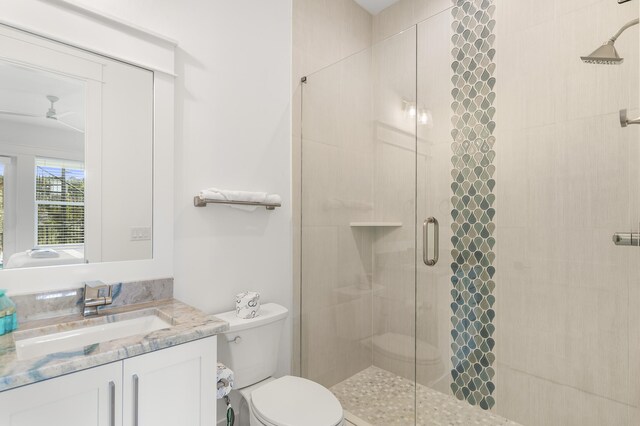 bathroom with ceiling fan, vanity, toilet, and an enclosed shower