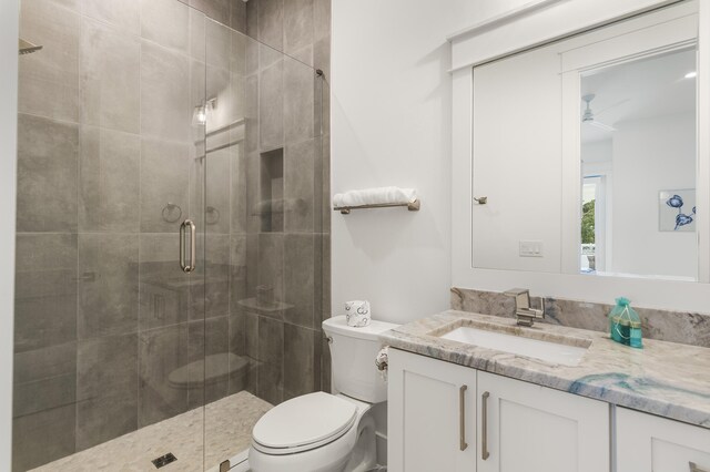 bathroom featuring ceiling fan, vanity, toilet, and an enclosed shower