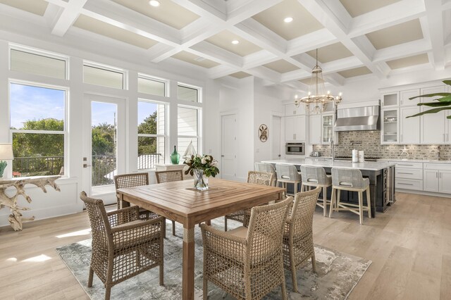 dining area with beam ceiling, a towering ceiling, a chandelier, and light wood-type flooring