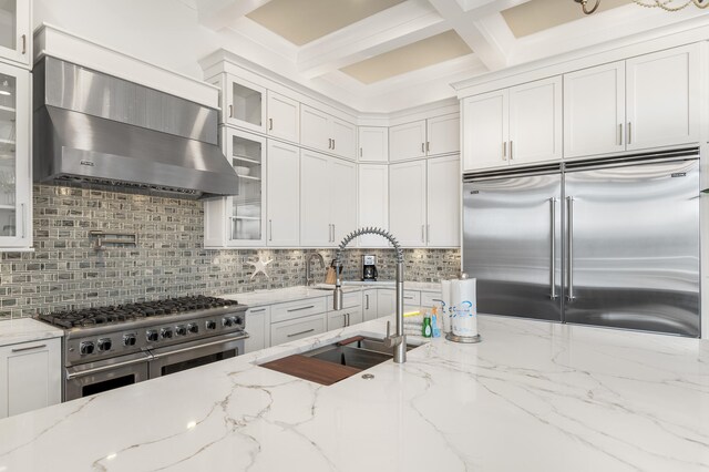 kitchen with white cabinetry, wall chimney exhaust hood, light stone countertops, and premium appliances