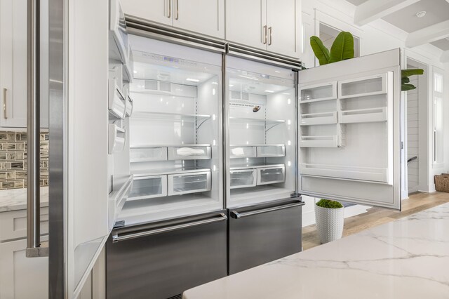 kitchen with white cabinetry, built in fridge, and light stone counters