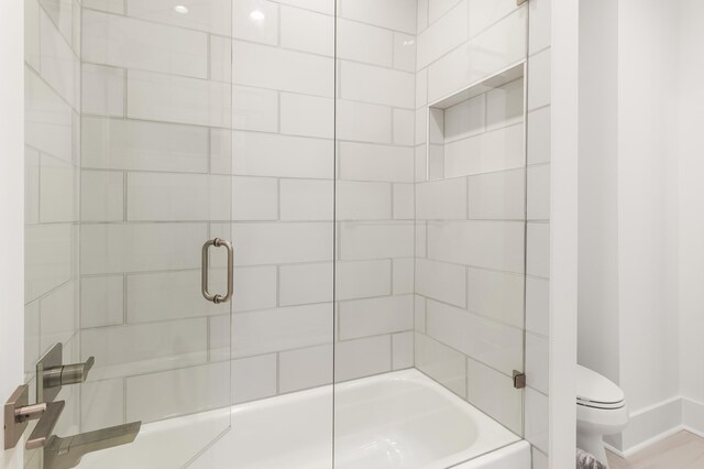 bathroom featuring shower / bath combination with glass door and toilet