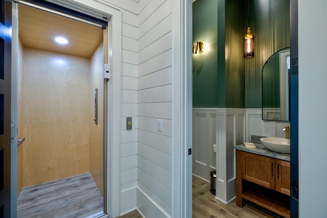 bathroom featuring hardwood / wood-style flooring, elevator, and vanity with extensive cabinet space