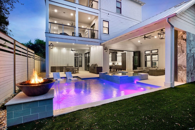 back of house with a patio, an outdoor living space with a fire pit, pool water feature, a balcony, and ceiling fan