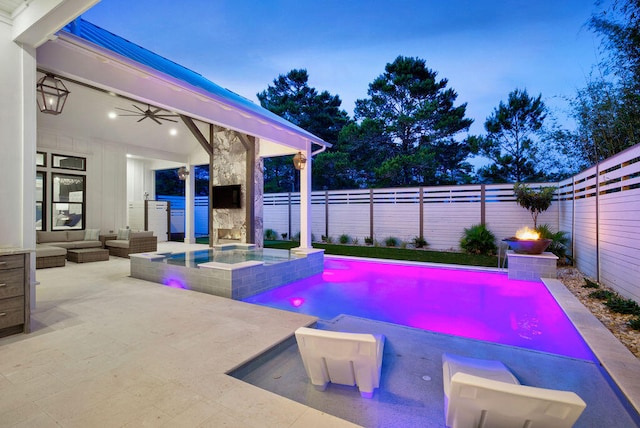 pool at dusk featuring a patio area, ceiling fan, an in ground hot tub, and an outdoor living space