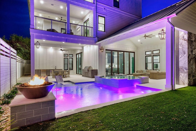 exterior space with ceiling fan, a patio, an outdoor living space with a fire pit, a balcony, and a lawn