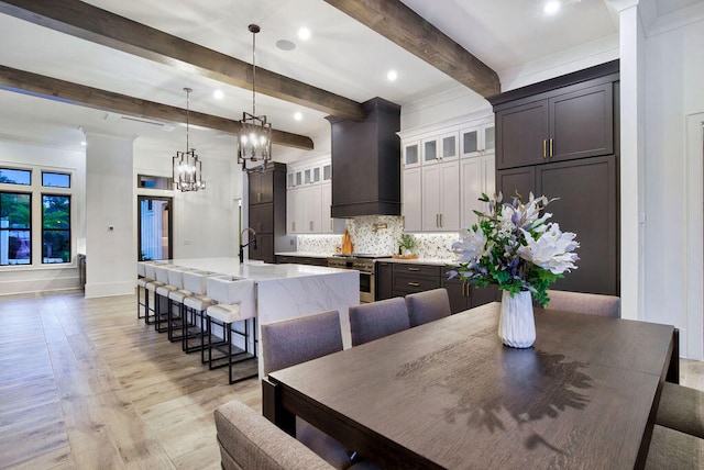 dining area with beamed ceiling, a notable chandelier, light hardwood / wood-style flooring, and sink