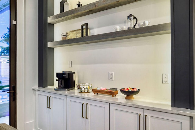 bar with white cabinets, light stone countertops, and a healthy amount of sunlight