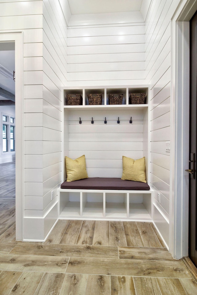 mudroom with wood walls and light hardwood / wood-style floors