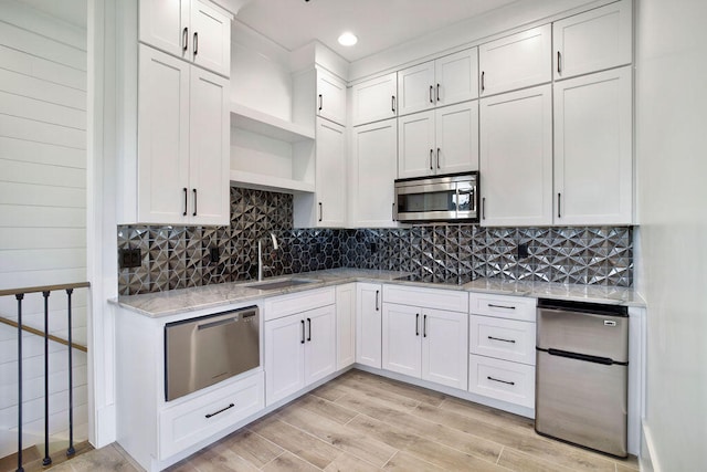 kitchen featuring appliances with stainless steel finishes, light hardwood / wood-style flooring, sink, and tasteful backsplash