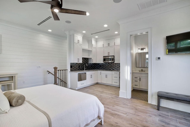 bedroom featuring light hardwood / wood-style floors, ceiling fan, sink, and ensuite bathroom