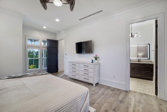 bedroom featuring ensuite bathroom, light hardwood / wood-style flooring, crown molding, sink, and a notable chandelier