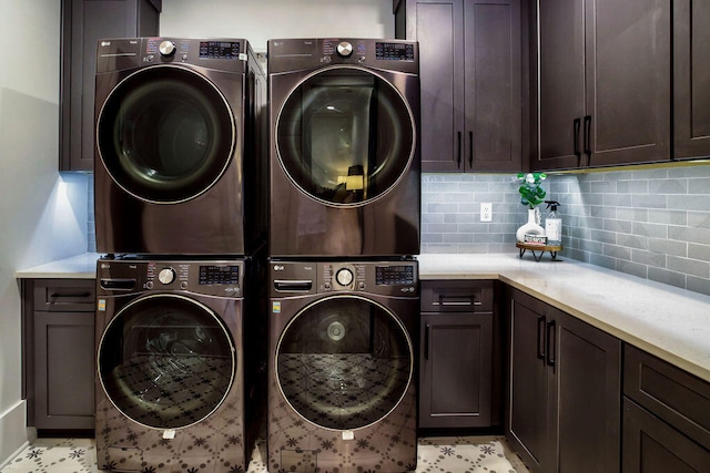 clothes washing area featuring stacked washer and clothes dryer, cabinets, and light tile floors