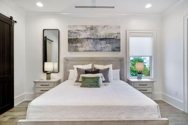 bedroom with light wood-type flooring and a barn door