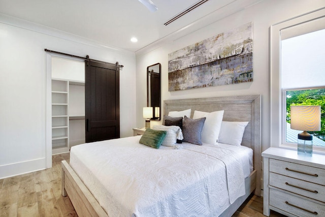 bedroom featuring light hardwood / wood-style flooring, a walk in closet, and a barn door