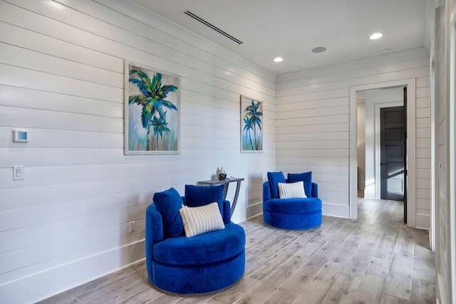 sitting room with light hardwood / wood-style floors and wooden walls