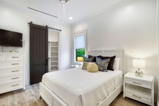 bedroom with light hardwood / wood-style flooring, ceiling fan, and a barn door