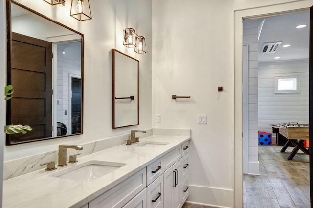 bathroom featuring wood-type flooring, oversized vanity, and double sink