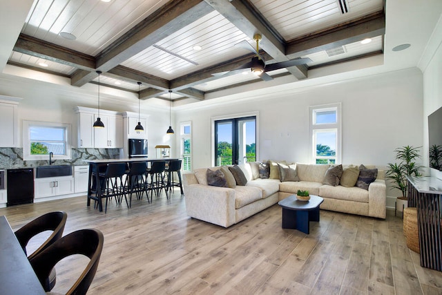 living room featuring beamed ceiling, sink, coffered ceiling, light hardwood / wood-style floors, and ceiling fan