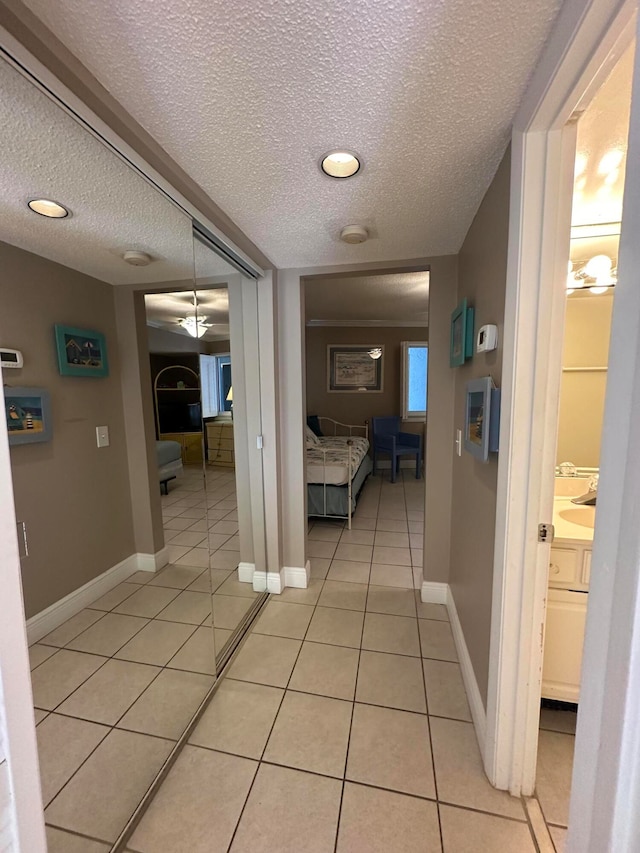 corridor featuring a textured ceiling and light tile flooring