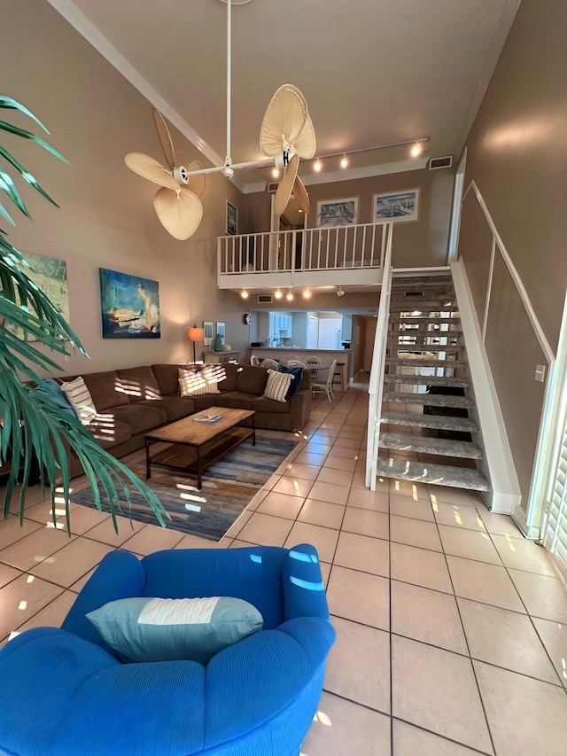 tiled living room with ceiling fan and crown molding