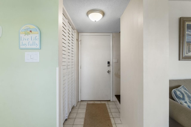 doorway featuring a textured ceiling and light tile floors