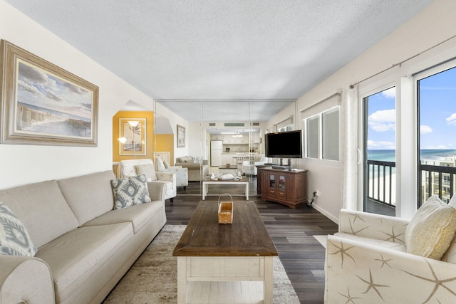 living room featuring dark wood-type flooring, a textured ceiling, and a water view